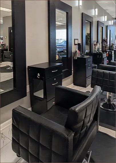 A modern hair salon interior with black styling chairs, large mirrors, and cabinets along a light-colored wall. - Pflugerville, TX
